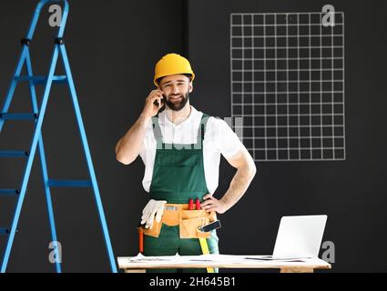 Construction worker talking by mobile phone in room Stock Photo
