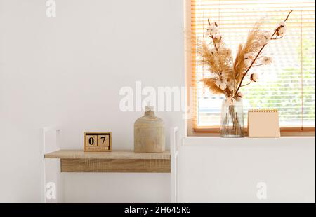 Vase with pampas grass and cotton branches on windowsill Stock Photo