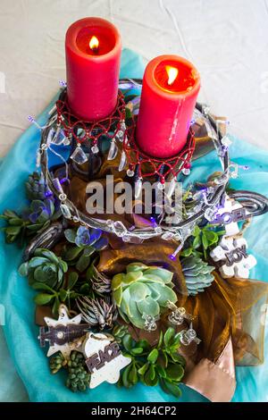 A nature inspired centerpiece for a with lit candles, and garden plants for an outdoor summer Christmas Table. Stock Photo