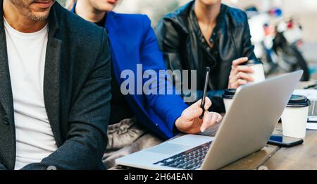 Group of corporate colleagues working together outdoors. Modern business professionals having a discussion during coffee break. Stock Photo
