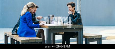 Group of corporate colleagues working together outdoors. Modern business professionals having a discussion during coffee break. Stock Photo
