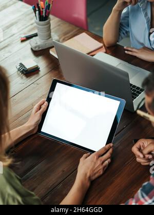 Mockup image of a female hands holding digital tablet with empty blank screen on wooden table. Copy space ready for text or design Stock Photo