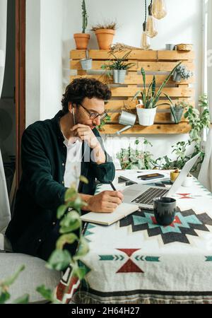 Handsome man with laptop working remotely from home. Freelancer at remote work. Cozy workplace Stock Photo