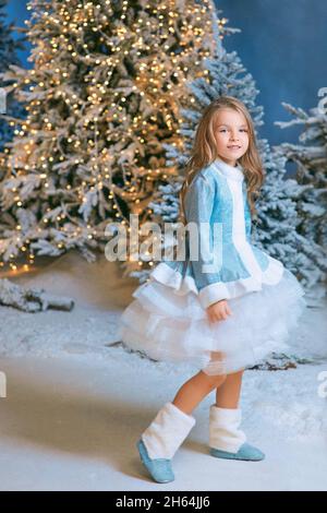 cute Caucasian blonde girl walking winter christmas forest with lights. New year, fairy tale concept Stock Photo