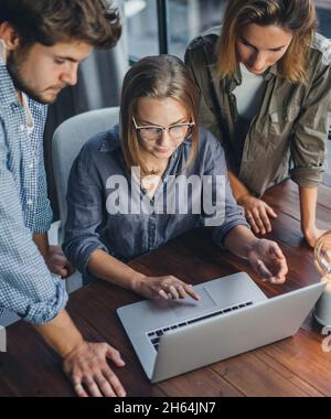 Group of young colleagues using laptop. People working or studying together. Business team in office. Teamwork. Startup concept Stock Photo