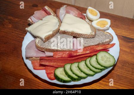 A plate with sandwiches and cucumber , peppers and eggs on the side Stock Photo