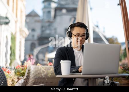 Businessman in earphones working on laptop in cafe Stock Photo