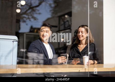 Multiracial couple drink coffee at table in cafe Stock Photo