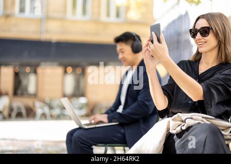Businessman work on laptop and woman go in city Stock Photo