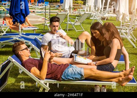 Friends relaxing on sun loungers in beautiful sunny day. Stock Photo