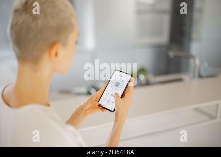 Girl using app of smart home on smartphone Stock Photo