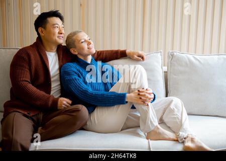 Multiracial couple sit and rest on sofa at home Stock Photo