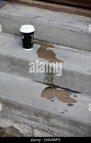 Paper coffee cup and spilled coffee on concrete stairs Stock Photo