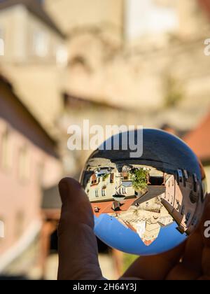 Hand holding glass sphere in front of old church in Weissenkirchen, Wachau (Austria), sunny day in autumn Stock Photo