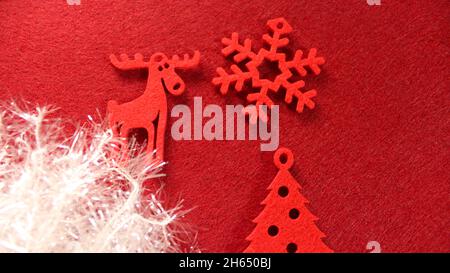 Christmas decoration: red Christmas decorations made of felt in the form of a Christmas tree, deer and snowflakes against a red background with white Stock Photo