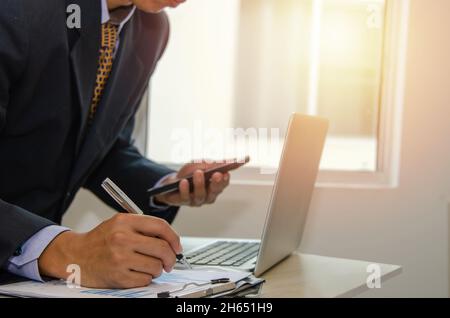 Business man holding a pen, business documents, reports, graphs and charts of financial statements and profit growth Stock Photo