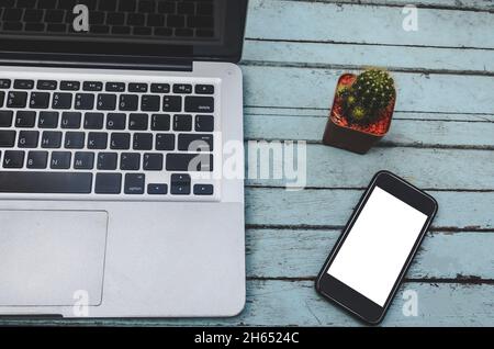 Laptop and smartphone and cactus on a wooden table. Vintage tone Stock Photo