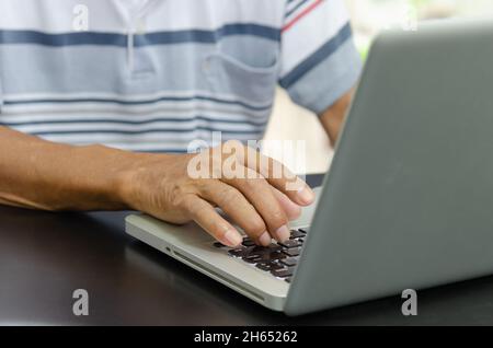 man hand using computer laptop on table at home, searching information  browsing the internet on web, work from home.Business concept Stock Photo