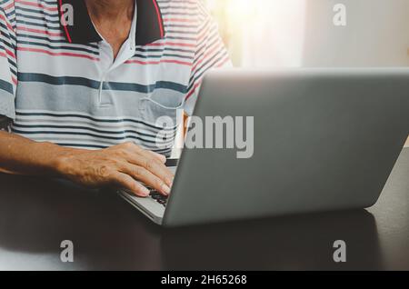 man hand using computer laptop on table at home, searching information  browsing the internet on web, work from home.Business concept Stock Photo