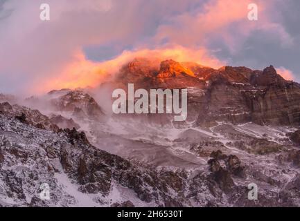 Bright orange and dark red dramatic sky over the rock summit of Aconcagua on sunset, the highest peak of South America, Argentina