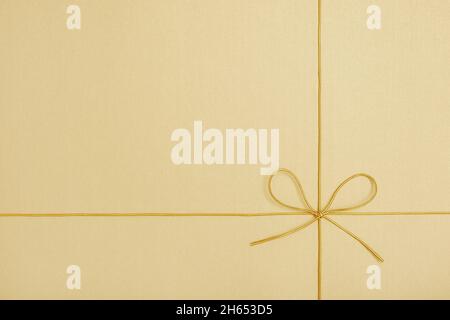 Shiny golden string tied in a bow on yellow background Stock Photo