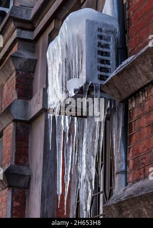Air conditioner covered with ice and icicles. Aged old house wall. Cold cooling concept. ?roblem with air conditioning in winter Stock Photo