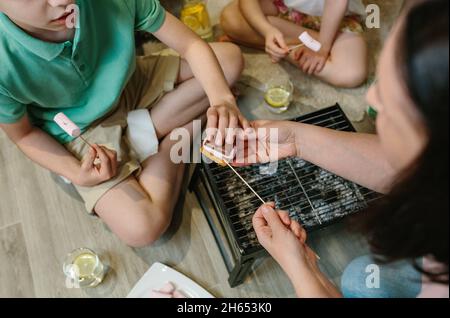Top view of unrecognizable family making smores at home Stock Photo