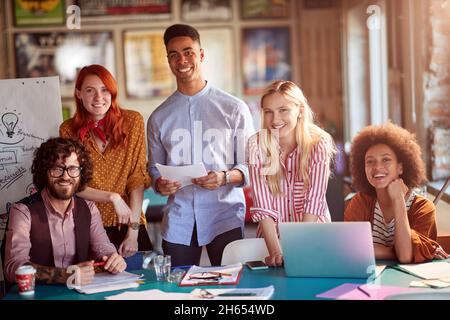 Group of happy employees are posing for a photo while working in a pleasant atmosphere in the office together Stock Photo