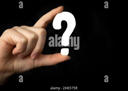 Question mark sign in hand. Question icon, symbol on a black background. Concept of doubt, education or FAQ Stock Photo