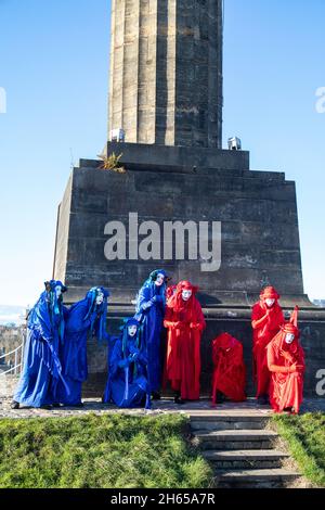 The Red Rebel Brigade join the Blue Rebel Brigade at the Glasgow Necropolis graveyard for the funerary of COP26. The weeping climate activists feel that COP26 is a failure and have held a mock funeral for the summit. COP26 is laid to rest in a grave alongside all of the previous COP summits. Stock Photo