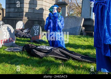 The Red Rebel Brigade join the Blue Rebel Brigade at the Glasgow Necropolis graveyard for the funerary of COP26. The weeping climate activists feel that COP26 is a failure and have held a mock funeral for the summit. COP26 is laid to rest in a grave alongside all of the previous COP summits. Stock Photo