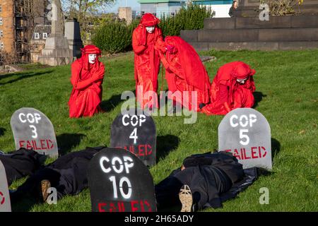 The Red Rebel Brigade join the Blue Rebel Brigade at the Glasgow Necropolis graveyard for the funerary of COP26. The weeping climate activists feel that COP26 is a failure and have held a mock funeral for the summit. COP26 is laid to rest in a grave alongside all of the previous COP summits. Stock Photo