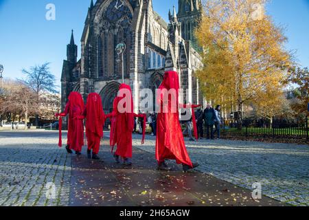 The Red Rebel Brigade join the Blue Rebel Brigade at the Glasgow Necropolis graveyard for the funerary of COP26. The weeping climate activists feel that COP26 is a failure and have held a mock funeral for the summit. COP26 is laid to rest in a grave alongside all of the previous COP summits. Stock Photo