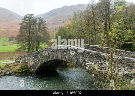 Attractive footbridge built of slate stone across the Derwent River near Rosthwaite village in Borrowdale, Lake District, Cumbria, England, UK Stock Photo