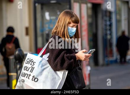 Dundee, Tayside, Scotland, UK. 13th Nov, 2021. UK Weather: With temperatures reaching 12°C in North East Scotland, it's a beautiful and sunny autumn day. This attractive young woman is texting messages on her phone while out shopping and enjoying the Autumn weather in Dundee city centre. Credit: Dundee Photographics/Alamy Live News Stock Photo
