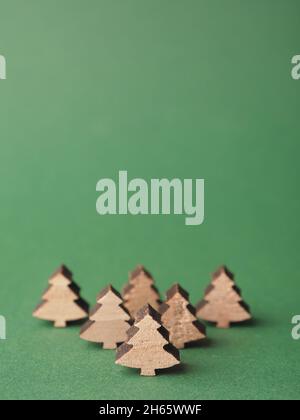 Small wooden Christmas tree shapes on a green paper background with space for your text Stock Photo