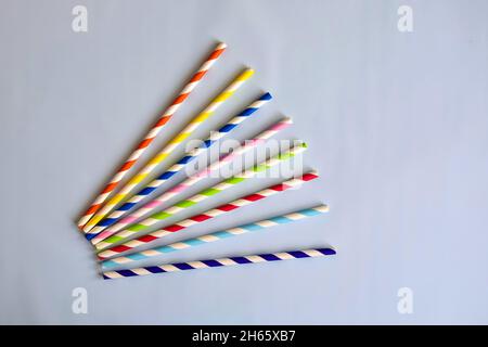 Disposable colorful striped paper cocktail sticks for party on blue background. Eco friendly paper drinking straws. It's choice for reduce plastic was Stock Photo