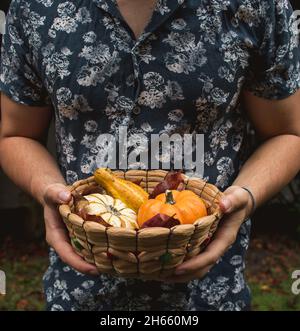 Fashionable hispanic young man holding mini-pumpkin and gourds on autumn leaves Stock Photo