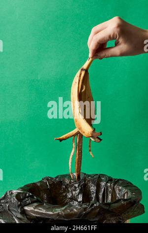 Woman throwing banana peels in trash can. Throw out banana peels in garbage. Banana skin in recycling bio bin in the kitchen Stock Photo