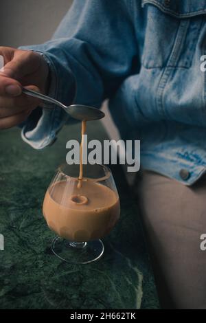 Fashionable young man hand model pouring cup of latte coffee with spoon Stock Photo