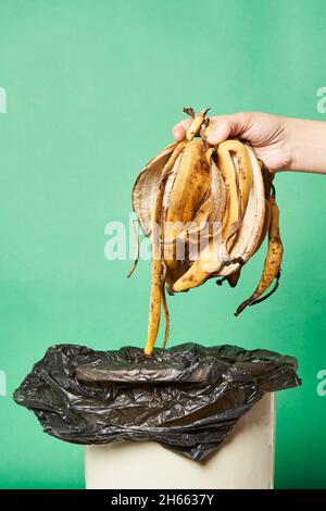 Woman throwing banana peels in trash can. Throw out banana peels in garbage. Banana skin in recycling bio bin in the kitchen Stock Photo