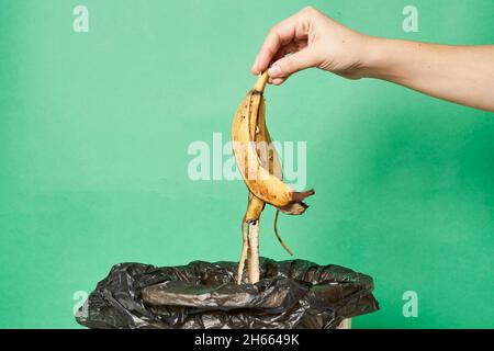 Woman throwing banana peels in trash can. Throw out banana peels in garbage. Banana skin in recycling bio bin in the kitchen Stock Photo