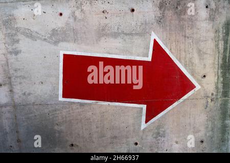 Red arrow painted on concrete wall Stock Photo