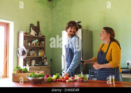 Happy young couple spending leisure time together while cooking meal in kitchen at home Stock Photo
