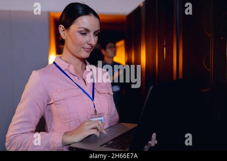 Caucasian female engineer using laptop in computer server room Stock Photo