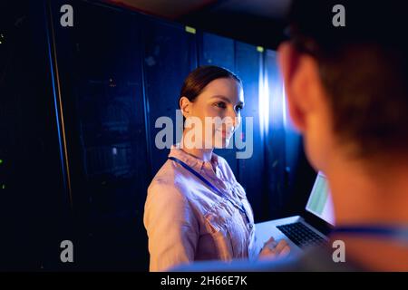 Caucasian female engineer using laptop in computer server room Stock Photo