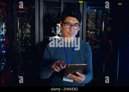 Asian male engineer using digital tablet in computer server room Stock Photo