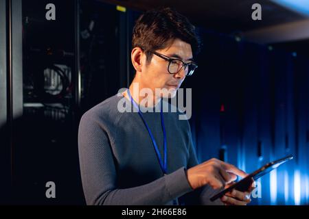 Asian male engineer using digital tablet in computer server room Stock Photo