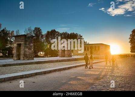 People walking and crossing the Cuartel de la Montana Park at sunset with the Temple of Debod in the background. Madrid, Spain. Stock Photo