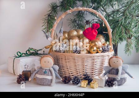 wicker basket filled with golden balls, gifts, toys and pine cones to decorate Christmas fir tree Stock Photo